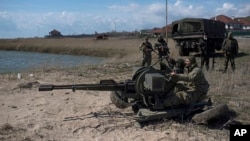 FILE - Ukrainian servicemen deploy a weapon at the beach of the Azov Sea in Shyrokyne, eastern Ukraine, April 15, 2015. 