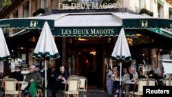 Pelanggan duduk di teras kafe dan restoran Les Deux Magots di Paris yang dibuka kembali setelah tutup selama berbulan-bulan di tengah pandemi COVID-19 di Perancis, 19 Mei 2021. (REUTERS / Christian Hartmann)