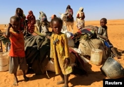 FILE - People set down their belongings as they arrive at the Zamzam IDP camp for Internally Displaced Persons (IDP), near El Fasher in North Darfur, Feb. 4, 2015.