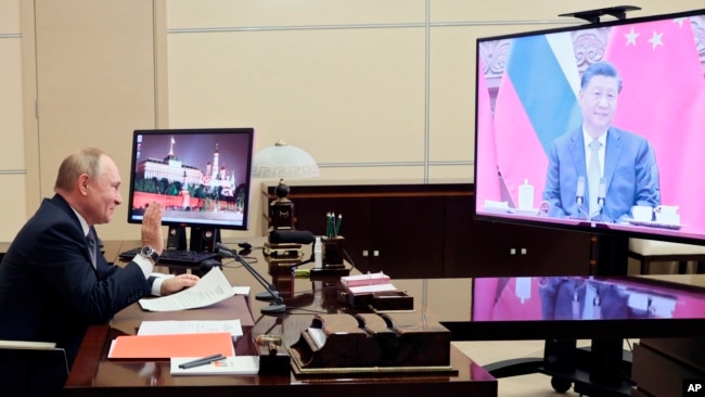 Russian President Vladimir Putin gestures during his videoconference with Chinese President Xi Jinping, right on the screen, in Moscow, Russia, Wednesday, Dec. 15, 2021. (Mikhail Metzel, Sputnik, Kremlin Pool Photo via AP)