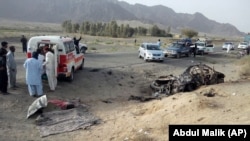 Volunteers stand near the wreckage of a destroyed vehicle, in which Mullah Akhtar Mansoor was allegedly traveling in the Ahmed Wal area in Baluchistan province of Pakistan, near the Afghanistan border, May 21, 2016.