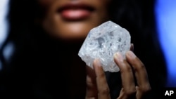 A model displays a large diamond at Sotheby's in New York, May 4, 2016. A 3-billion-year-old diamond the size of a tennis ball — the largest discovered in over a century — could sell for more than $70 million, auctioneer Sotheby's said Wednesday.