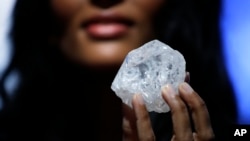 A model displays a large diamond at Sotheby's in New York, May 4, 2016. A 3-billion-year-old diamond the size of a tennis ball — the largest discovered in over a century — could sell for more than $70 million, auctioneer Sotheby's said Wednesday.