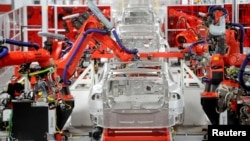 FILE - Robotic arms assemble Tesla's Model S sedans at the company's factory in Fremont, California, June 22, 2012. 
