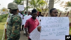 Protesters walk past a soldier standing guard during a rally against the decision to end fuel subsidies in Nigeria's capital Abuja, January 6, 2012.
