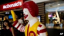 FILE - In this Thursday, July 31, 2014 file photo, a customer walks past a statue of Ronald McDonald on display outside a McDonald's restaurant in Beijing. McDonald's Corp. on Monday, Nov. 10, 2014 said that a key global sales figure slipped 0.5 percent in October, with weakness in the U.S. and ongoing difficulties from a food-safety scandal in China weighing down its business. (AP Photo/Andy Wong, File)