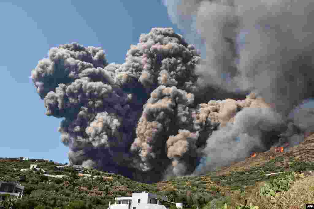 Smoke billows and flames propagate across the hillside near houses after the Stromboli volcano erupted, July 3, 2019, on the Stromboli island, north of Sicily.