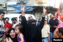 A woman flashes the victory sign as she celebrates the news of the breaking of the siege of rebel-held areas of Aleppo, Aug. 6, 2016.