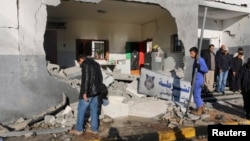 Civilians and security personnel stand at the scene of an explosion at a police station in Tripoli, Libya, a blast later claimed by militants professing loyalty to Islamic State, March 12, 2015. 