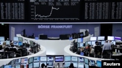 Traders are at their desks in front of the DAX board at the Frankfurt stock exchange, Aug. 14, 2014.