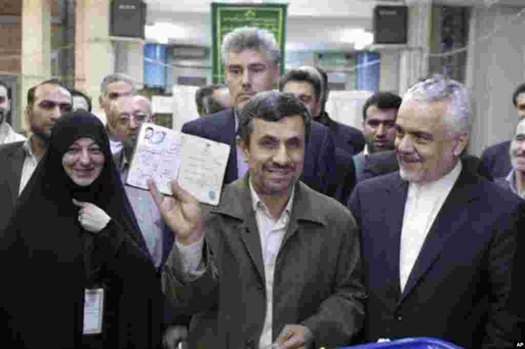 Iranian President Mahmoud Ahmadinejad shows his identification document after casting his ballot for the parliamentary elections at a polling station, while Vice-President Mohammad Reza Rahimi, right, looks on, in downtown Tehran, Iran, Friday, March 2, 2
