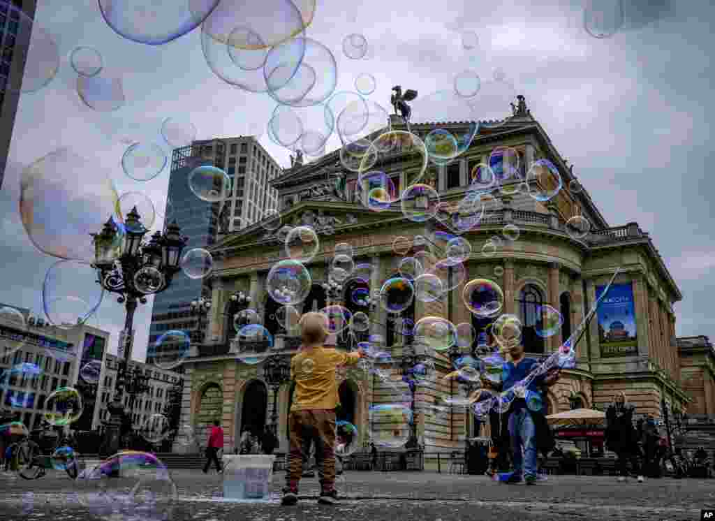A boy plays with bubbles made by a soap bubble artist in front of the Old Opera in Frankfurt, Germany.