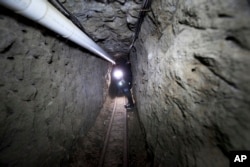 FILE - Federal Police officer stands in the tunnel where according to authorities drug lord Joaquin "El Chapo" Guzman made his escape from the Altiplano maximum security prison in Almoloya, west of Mexico City, July 16, 2015.