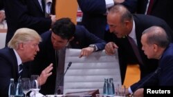 U.S. President Donald Trump, left, Turkish President Recep Tayyip Erdogan and Turkey's Foreign Minister Mevlut Cavusoglu, standing right, talk during the working session at the G-20 leaders summit in Hamburg, Germany, July 7, 2017. 