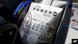 FILE - A Powerball lottery ticket is printed out of a lottery machine at a convenience store in Chicago, Illinois. 