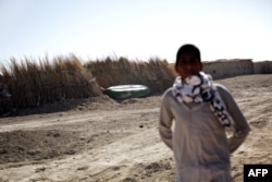 FILE - An Iranian man looks toward an abandoned boat in Sikh Sar village at the Hamoon wetland near the Zabol town in Sistan-Baluchistan province, Feb. 2, 2015.