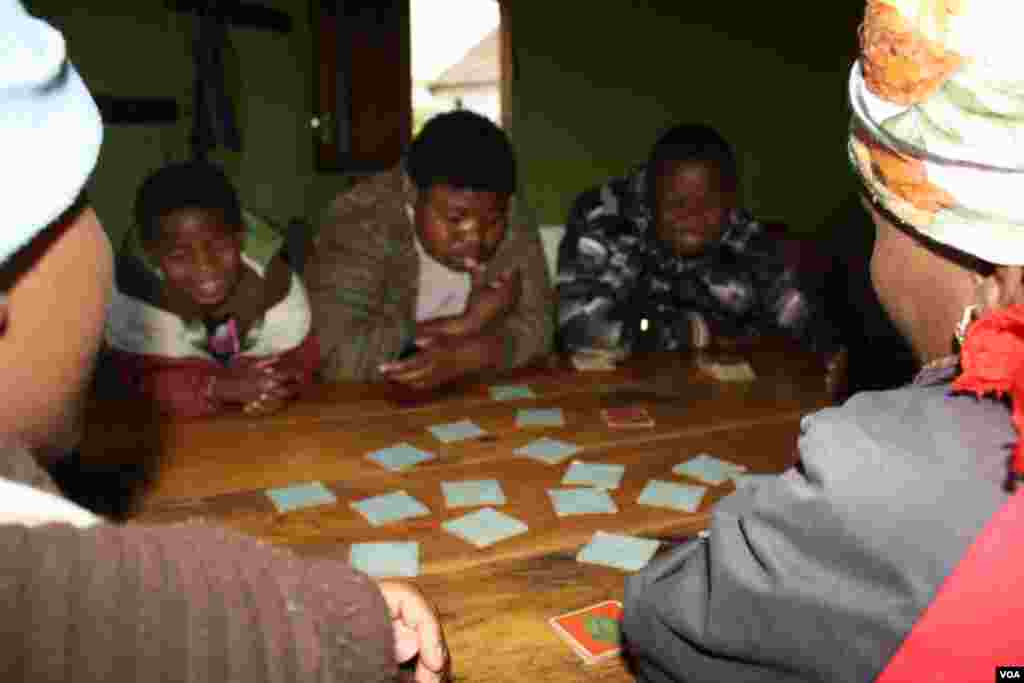 Caregivers watch patients play a card game at Ikhaya Loxolo (VOA/Taylor) 