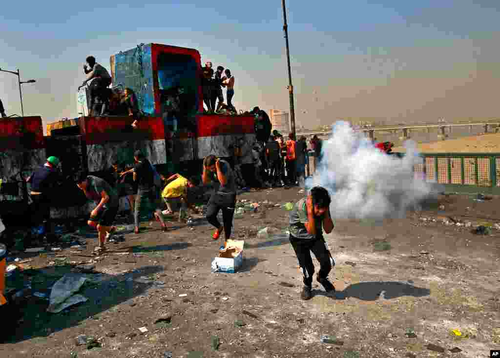 Security forces fire sound bombs to disperse anti-government protesters on the closed Joumhouriya Bridge that leads to the Green Zone government areas, near Tahrir square, Baghdad, Iraq.