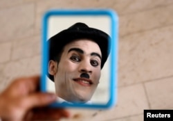 Afghanistan's Charlie Chaplin, Karim Asir, 25, reacts in a mirror before his performance in Kabul, Afghanistan, Aug. 29, 2018.