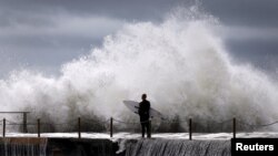 A cyclonic storm lashed Australia's east coast for a third day Wednesday, causing millions of dollars of damage to property and infrastructure. A surfer waits for a break in crashing waves before diving in for a surf off Sydney's Collaroy Beach, April 22,