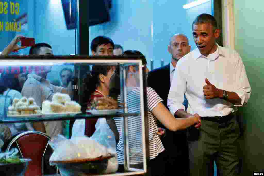 Presiden AS Barack Obama berjabat tangan dengan warga lokal saat meninggalkan sebuah restoran yang menyajikan bun cha, makanan tradisional Vietnam yang terdiri dari mie dan babi panggang, di Hanoi, Vietnam (23/5). (Reuters/Carlos Barria)