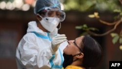 A health worker collects a swab sample from a woman at a Covid-19 coronavirus screening site in New Delhi on October 29, 2020. - India on October 29 passed eight million coronavirus cases, with the world's second-worst-hit country bracing for a possible s