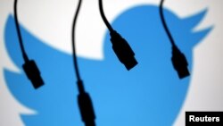 FILE - Electronic cables are silhouetted next to the logo of Twitter, Sept. 23, 2014. 
