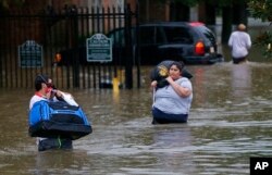 FILE - Residents wade through floodwater in the Chateau Wein Apartments in Baton Rouge, Louisiana, Aug. 12, 2016.