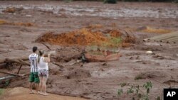 A couple with missing relatives look at the flooded area, after a dam collapsed in Brumadinho, Brazil, Jan. 26, 2019. 
