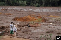 A couple with missing relatives look at the flooded area, after a dam collapsed in Brumadinho, Brazil, Jan. 26, 2019.