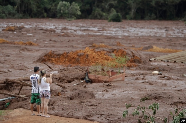 A couple with missing relatives look at the flooded area, after a dam collapsed in Brumadinho, Brazil, Jan. 26, 2019.