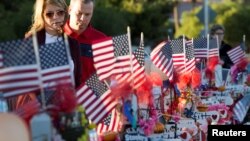 FILE - A couple looks over 58 wooden crosses, with the names and photos of the October 1 mass shooting victims, in the median of Las Vegas Boulevard South near the "Welcome to Las Vegas" sign in Las Vegas, Nevada, Oct. 9, 2017.