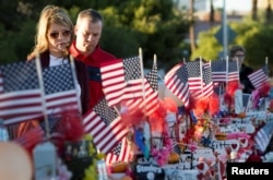 A couple looks over 58 wooden crosses, with the names and photos of the October 1 mass shooting victims, in the median of Las Vegas Boulevard South near the "Welcome to Las Vegas" sign in Las Vegas, Nevada, Oct. 9, 2017.
