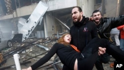 FILE - A man carries an injured woman away from the site of a car bomb explosion in a Shiite southern suburb of Beirut, Jan. 2, 2014. 