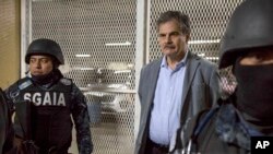 Juan Alberto Fuentes, former Guatemalan Minister of Finance and currently chair of the NGO Oxfam International, is flanked by police as they wait to enter a holding cell in a courthouse, in Guatemala City, Tuesday, Feb. 13, 2018.