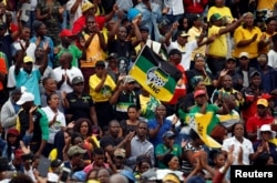 FILE - Supporters of the ANC wave a flag during the party's 106th anniversary celebrations, in East London, South Africa, Jan. 13, 2018. Analysts say Cyril Ramaphosa, in his efforts to sideline Jacob Zuma, must be careful not to wreak too much dissension in the party ahead of next year's general elections.