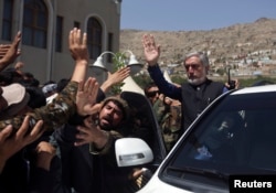 Afghan presidential candidate Abdullah Abdullah (R) waves after a ceremony commemorating the 2001 assassination of legendary Tajik resistance commander Ahmad Shah Massoud, in Kabul, Afghanistan, Sept. 9, 2014.