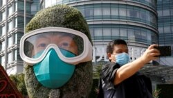 A man wearing a face mask takes selfies in front of a floral installation featuring a medical worker in the fight against the coronavirus disease, set up ahead of Chinese National Day on October 1, on Changan Avenue in Beijing, China.