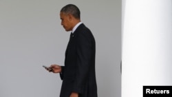 In this file photo, President Barack Obama checks his Blackberry smartphone upon his return from a trip to New York, as he walks into the West Wing of the White House in Washington, May 15, 2014. REUTERS/Jim Bourg