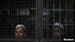 FILE - Rohingya Muslim illegal immigrants look out from the Immigration Detention Center in Kanchanaburi province, Thailand, July 10, 2013.