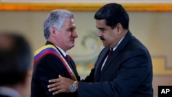 Cuba's President Miguel DIaz-Canel, left, is embraced by his Venezuelan counterpart Nicolas Maduro after being awarded the "Orden del Libertador Simon Bolivar," at Miraflores Presidential Palace in Caracas, Venezuela, May 30, 2018. 