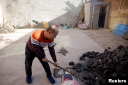 A man shovels coal he uses to heat his home in his courtyard in the village of Heqiaoxiang outside of Baoding, Hebei province, China, Dec. 5, 2017.