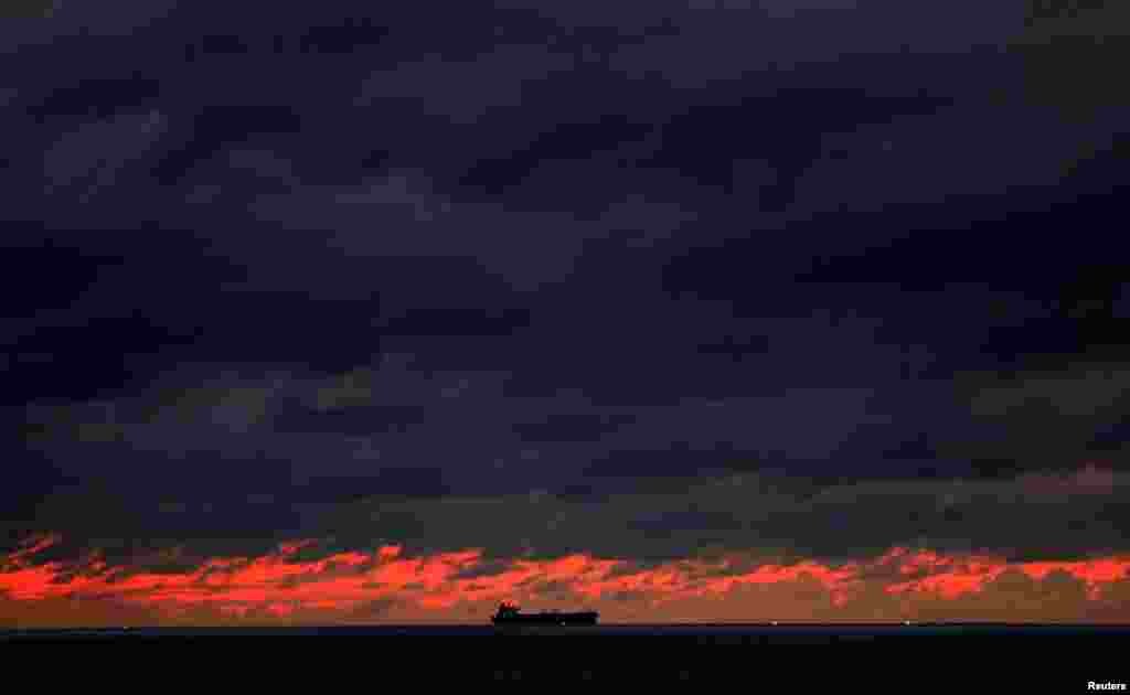 A ship sails towards Colombo main harbor as the dark clouds gathered above the sunset are seen from Galle Dutch Fort in Galle, Sri Lanka.