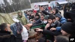 Migrants gather to get warm clothes inside a logistics center at the checkpoint "Kuznitsa" at the Belarus-Poland border near Grodno, Belarus, Nov. 28, 2021.