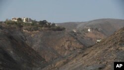 A home stands alone, at left, among the devastation left behind by a wildfire, Nov. 12, 2018, in Malibu, California. 