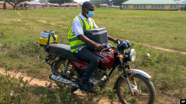 Yunusa Bawa, a community health worker, rides on a motorbike with a box of AstraZeneca coronavirus vaccines, in Sabon Kuje on the outskirts of Abuja, Nigeria, Dec 6, 2021.