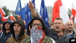 FILE - Protesters shout anti-migrant slogans as several thousand right-wing nationalists rally, demonstrating against EU proposed quotas for Poland to spread the human tide of refugees around Europe, in Warsaw, Poland, Sept. 12, 2015.