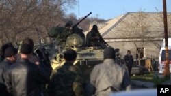 FILE - Soldiers in unmarked uniforms sit atop APC at the gate of the Belbek base near the port city of Sevastopol, Crimea, March 22, 2014. 