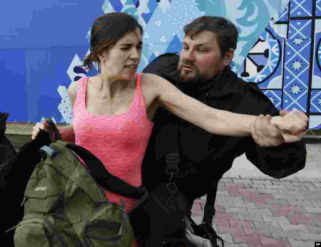 Nadezhda Tolokonnikova is pulled away by a Russian security officer after she and fellow members of the punk group Pussy Riot staged a protest performance, Sochi, Russia, Feb. 19, 2014. 