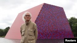 FILE - Artist Christo stands in front of his work The London Mastaba, on the Serpentine in Hyde Park, London, June 18, 2018.